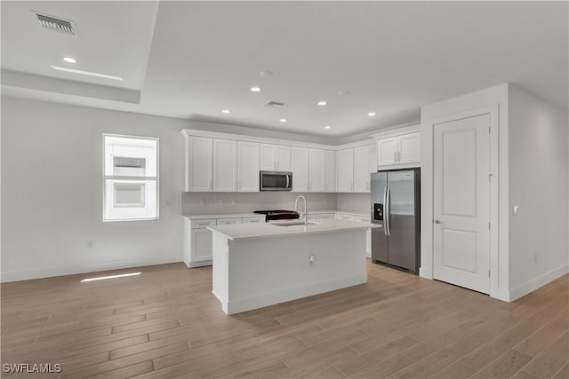 44287 Panther Dr, Punta Gorda, FL 33982 - kitchen with appliances with stainless steel finishes, light countertops, light wood-type flooring, a sink, and white cabinetry