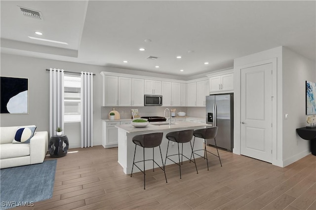 44287 Panther Dr, Punta Gorda, FL 33982 - kitchen featuring stainless steel appliances, light wood finished floors, white cabinetry, a kitchen breakfast bar, and light countertops