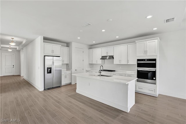 kitchen with stainless steel appliances, under cabinet range hood, light wood finished floors, light countertops, and recessed lighting
