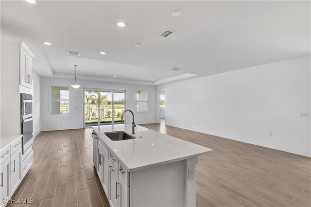 kitchen featuring a sink, open floor plan, light wood-style floors, healthy amount of natural light, and recessed lighting