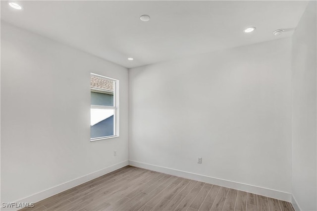 empty room with light wood-type flooring, baseboards, recessed lighting, and a smoke detector