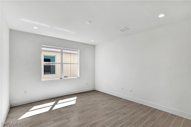 empty room featuring wood finished floors, baseboards, and recessed lighting