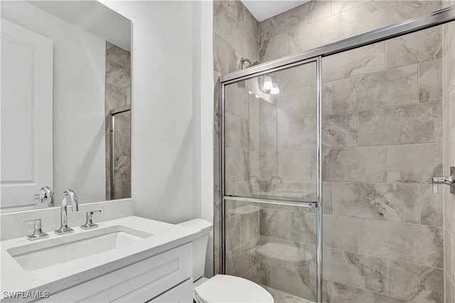 bathroom with toilet, a stall shower, and vanity