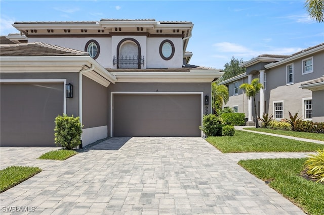 9380 Triana Ter Unit 312, Fort Myers, FL 33912 - mediterranean / spanish-style house featuring decorative driveway, stucco siding, an attached garage, and a front yard