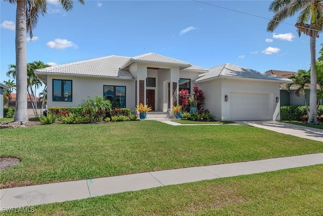 prairie-style house with an attached garage, a tile roof, driveway, and a front lawn