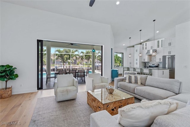 living room with a ceiling fan, light wood-style floors, recessed lighting, baseboards, and high vaulted ceiling