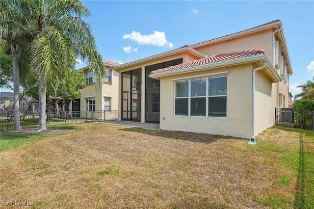 rear view of property with stucco siding, a sunroom, and central AC