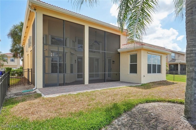back of property with a sunroom, stucco siding, a tile roof, and a patio area