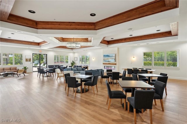dining space with a raised ceiling, light wood-style floors, a chandelier, and baseboards