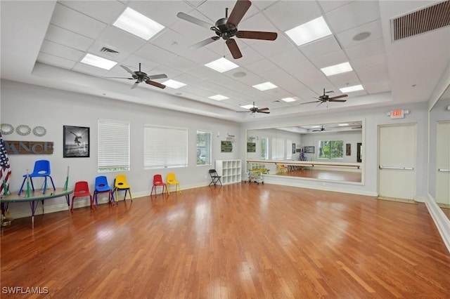 exercise area featuring ceiling fan, wood finished floors, a paneled ceiling, and baseboards