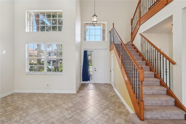 foyer entrance with a high ceiling, stairs, and baseboards