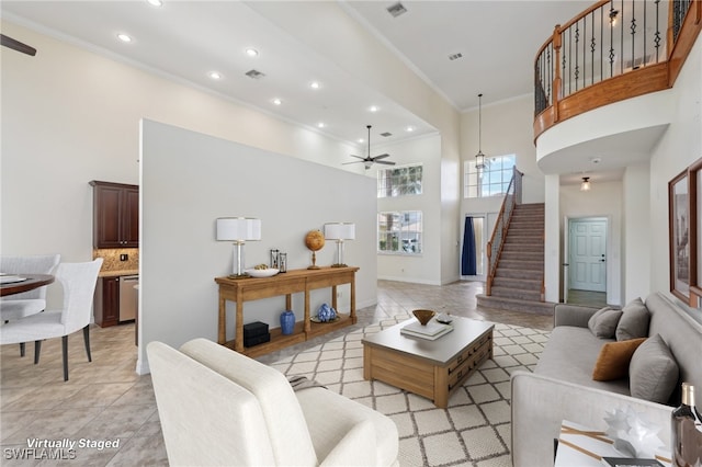 living area featuring a towering ceiling, ornamental molding, stairway, recessed lighting, and a ceiling fan