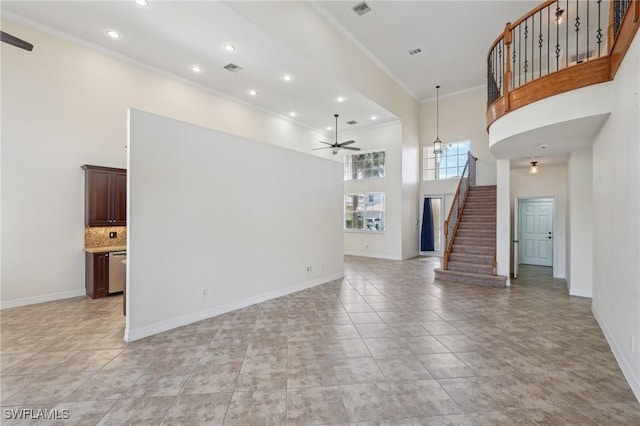 unfurnished living room featuring ceiling fan, stairway, a towering ceiling, ornamental molding, and baseboards