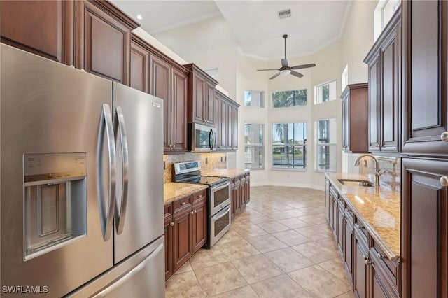 kitchen featuring appliances with stainless steel finishes, a sink, ceiling fan, light tile patterned floors, and decorative backsplash
