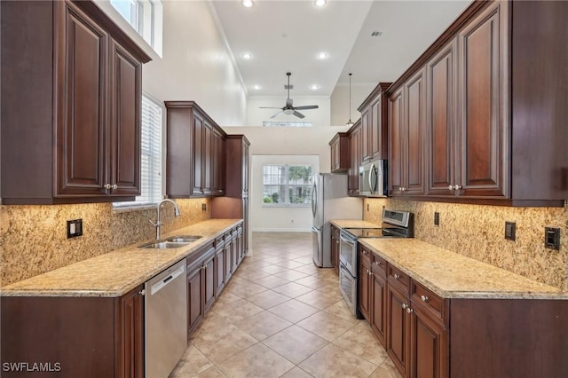kitchen featuring appliances with stainless steel finishes, a sink, ceiling fan, light tile patterned floors, and backsplash