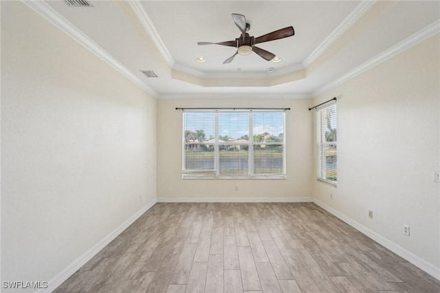 spare room featuring plenty of natural light, wood finished floors, a raised ceiling, ceiling fan, and ornamental molding