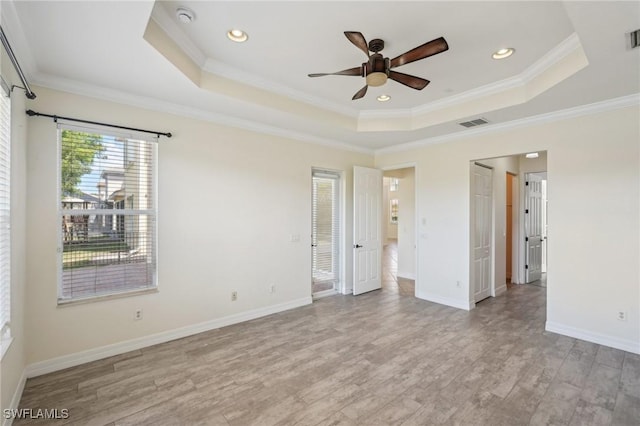 unfurnished bedroom with a raised ceiling, crown molding, light wood-type flooring, baseboards, and recessed lighting