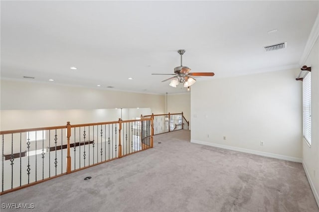 empty room with ceiling fan, carpet, baseboards, and crown molding