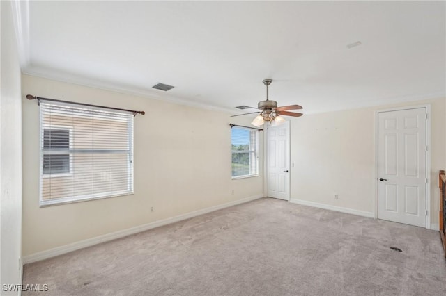 carpeted spare room featuring ornamental molding, ceiling fan, and baseboards
