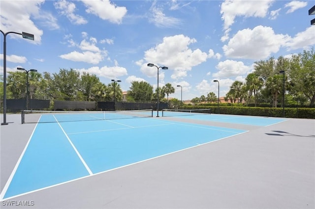 view of tennis court featuring community basketball court and fence