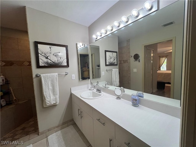 ensuite bathroom featuring a walk in shower, tile patterned floors, baseboards, and vanity