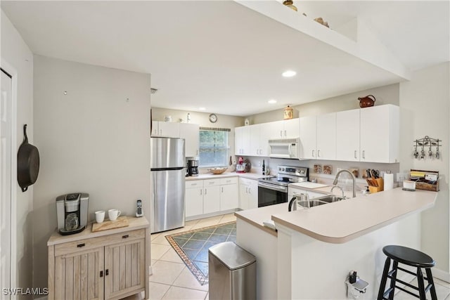 kitchen featuring appliances with stainless steel finishes, a peninsula, a breakfast bar area, light countertops, and light tile patterned floors