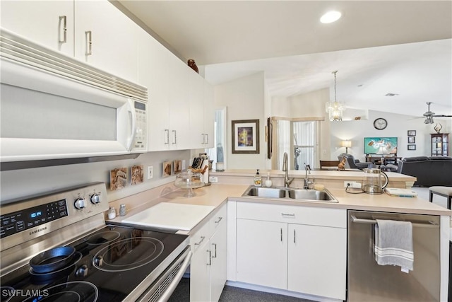 kitchen featuring appliances with stainless steel finishes, a sink, open floor plan, a peninsula, and white cabinets