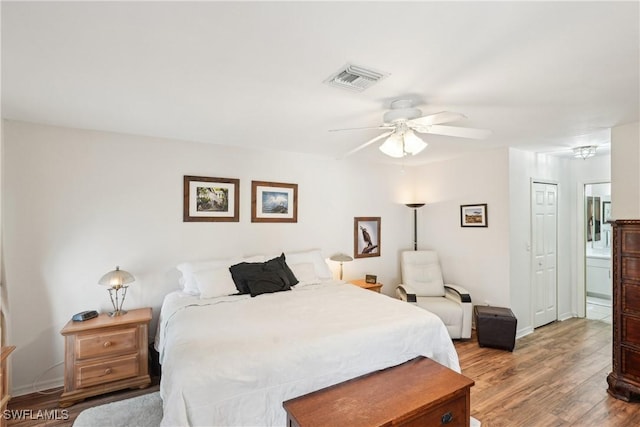 bedroom featuring wood finished floors, ensuite bath, and a ceiling fan