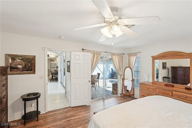 bedroom featuring access to outside, wood finished floors, a ceiling fan, and baseboards