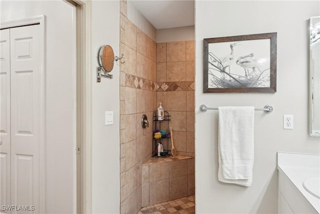 bathroom with a tile shower, a closet, and vanity