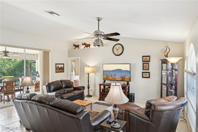 living area with a ceiling fan, healthy amount of natural light, vaulted ceiling, and light tile patterned flooring