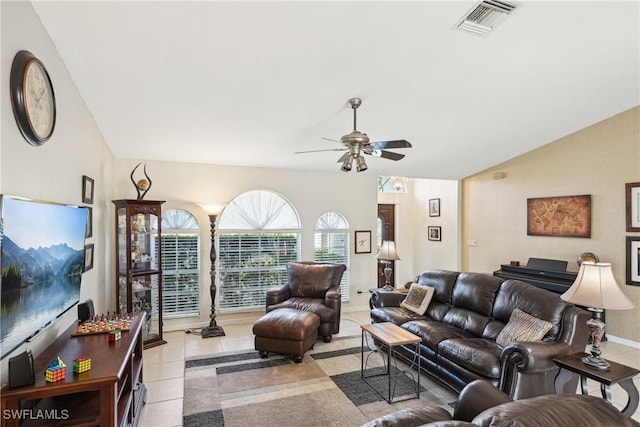 tiled living area with a ceiling fan, vaulted ceiling, and baseboards