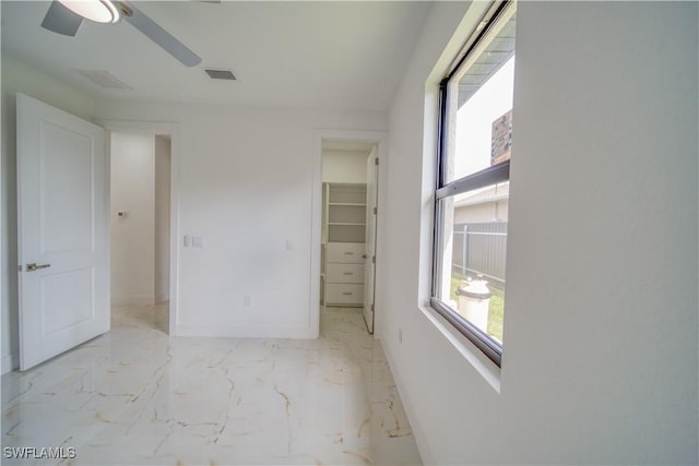710 SW 25th Ln, Cape Coral, FL 33914 - unfurnished bedroom featuring a spacious closet, baseboards, light marble finish flooring, and ceiling fan