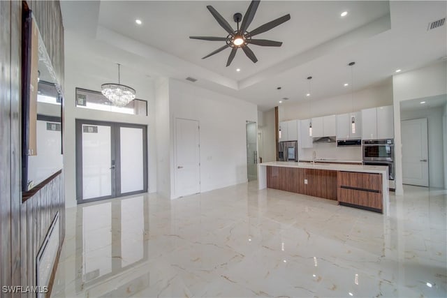 710 SW 25th Ln, Cape Coral, FL 33914 - kitchen with a towering ceiling, modern cabinets, light marble finish floors, a raised ceiling, and stainless steel double oven