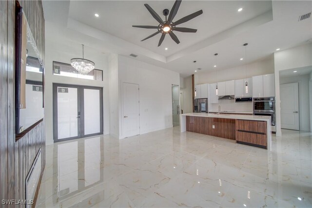 710 SW 25th Ln, Cape Coral, FL 33914 - kitchen featuring a high ceiling, modern cabinets, a tray ceiling, light marble finish floors, and double oven
