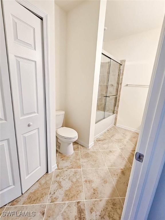 2685 Citrus St, Naples, FL 34120 - bathroom featuring toilet, baseboards, tile patterned flooring, and shower / bath combination with glass door