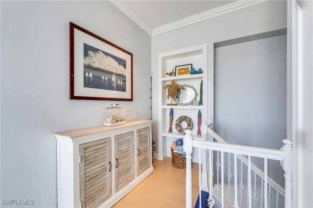hallway featuring ornamental molding, an upstairs landing, light wood-style floors, and built in features