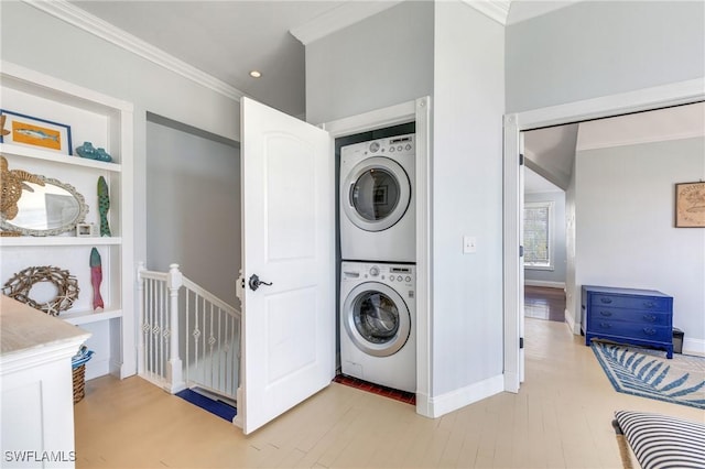 laundry room with stacked washer / dryer, light wood-type flooring, ornamental molding, built in shelves, and baseboards