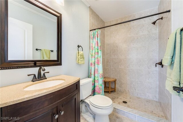 full bath featuring tiled shower, vanity, and toilet