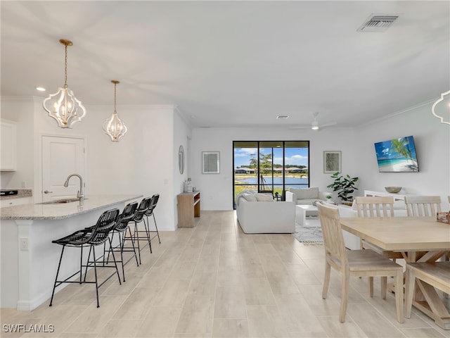 dining room featuring a chandelier, crown molding, light wood-style flooring, and a ceiling fan