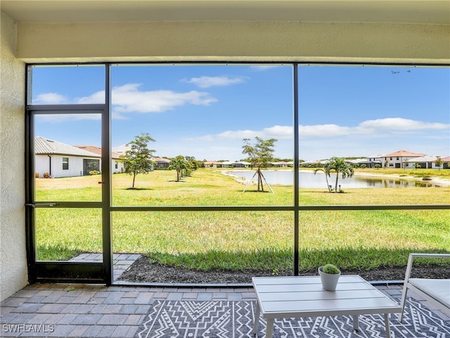 unfurnished sunroom featuring a water view and a residential view