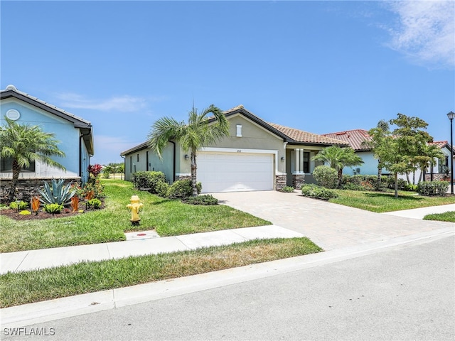 view of front of house featuring stone siding, an attached garage, a front yard, stucco siding, and driveway
