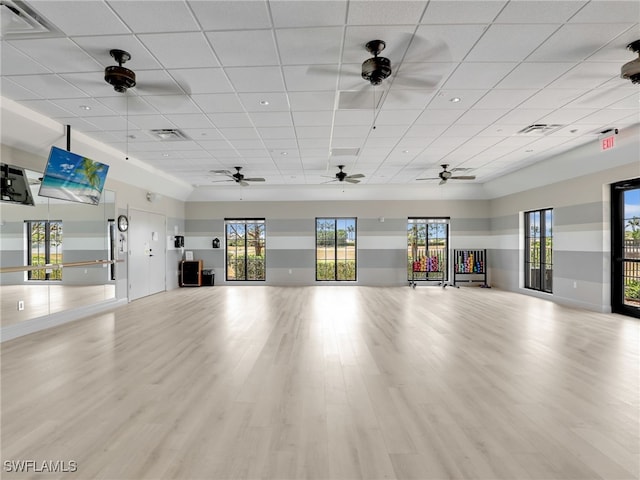 workout area with a paneled ceiling, plenty of natural light, wood finished floors, and ceiling fan