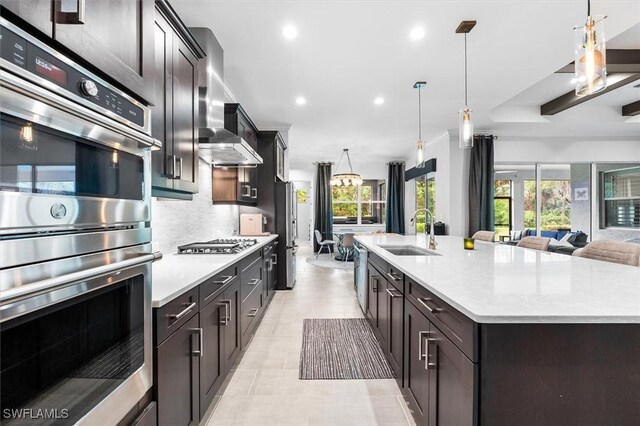 kitchen featuring a sink, appliances with stainless steel finishes, open floor plan, light countertops, and recessed lighting