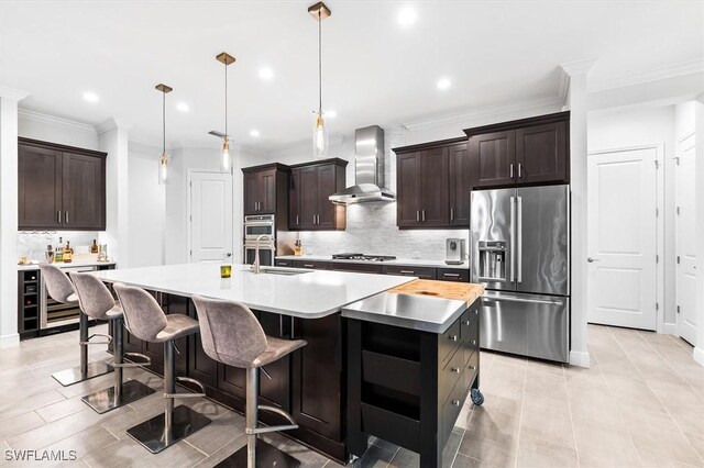 kitchen with appliances with stainless steel finishes, wall chimney range hood, a sink, decorative backsplash, and a spacious island