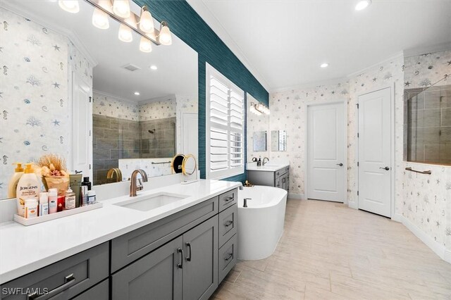 full bathroom with wallpapered walls, crown molding, a shower stall, two vanities, and a freestanding bath