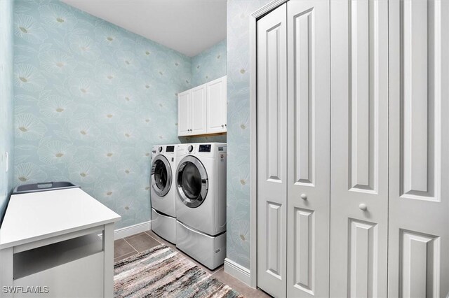 laundry room featuring cabinet space, washing machine and dryer, wallpapered walls, baseboards, and light tile patterned flooring