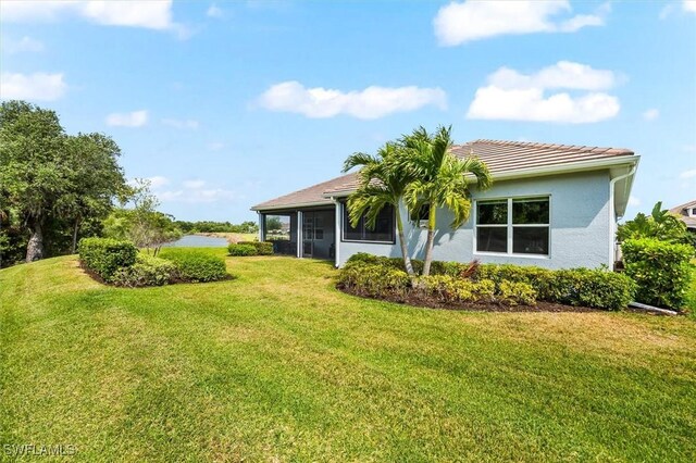 back of house with a yard, stucco siding, and a tile roof