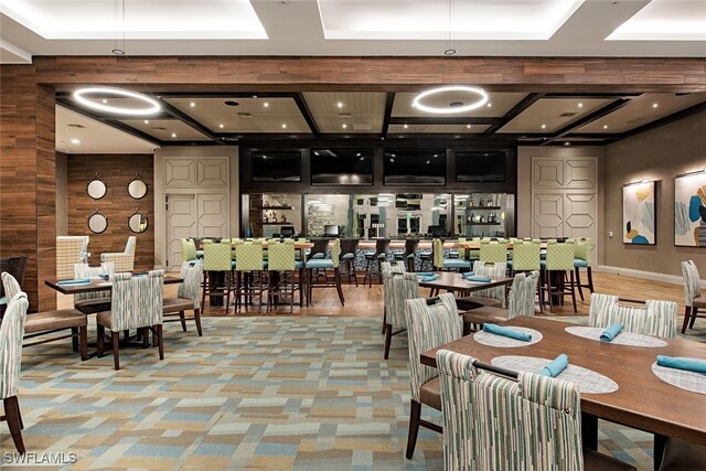carpeted dining room with coffered ceiling, wooden walls, and recessed lighting