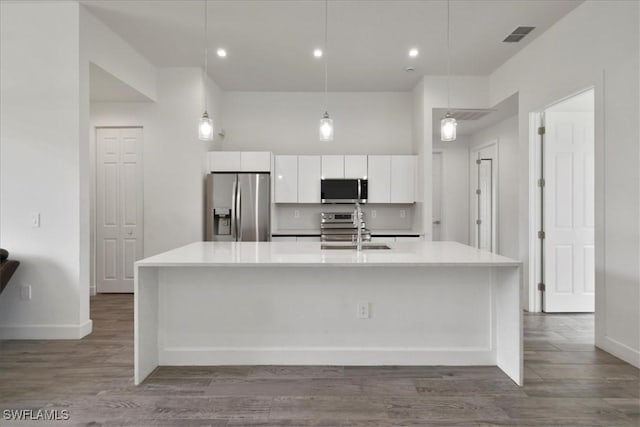 409 Columbus Blvd S, Lehigh Acres, FL 33974 - kitchen featuring appliances with stainless steel finishes, white cabinetry, a sink, a large island with sink, and light countertops